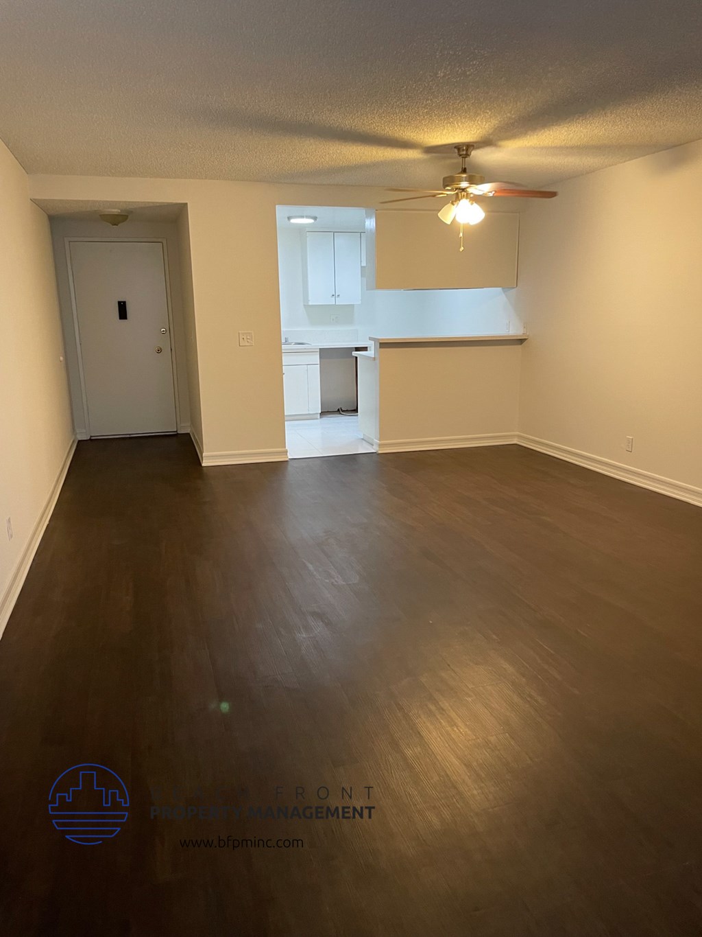 an empty living room with wood floors and a ceiling fan